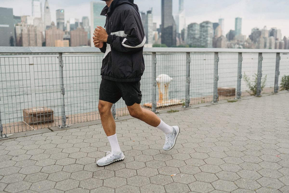Man running beside the waterfront in dark sportswear.