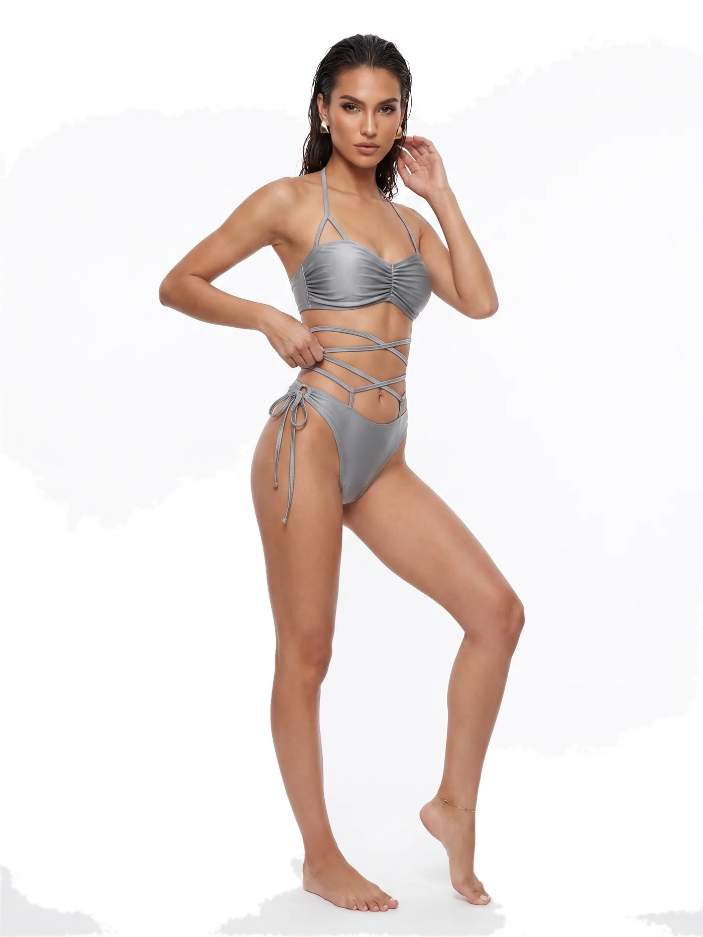 A silver bikini with long ties wrapped around the waist, photographed on a white studio ground.